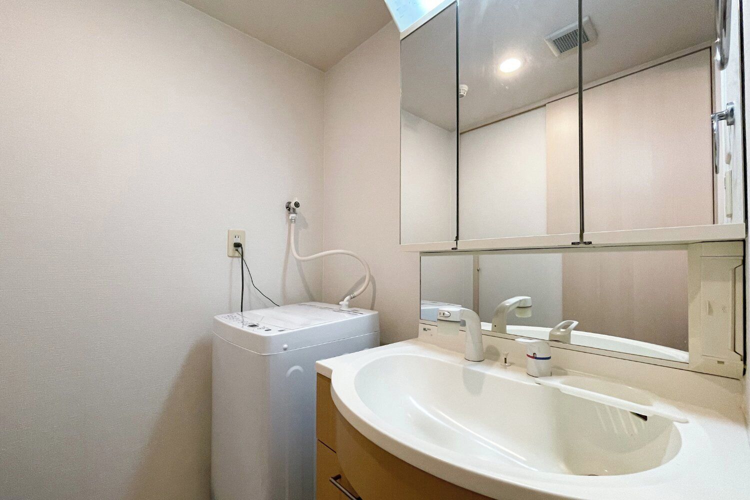 A bathroom with a white sink, mirror, and a white washing machine.