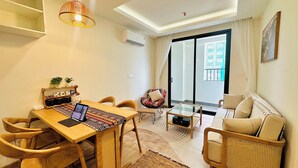 A modern living room with a dining area, a sofa, a coffee table, and a laptop on the table. - Boho and Cozy Home in Sapa -5Min to Center (Sapa)