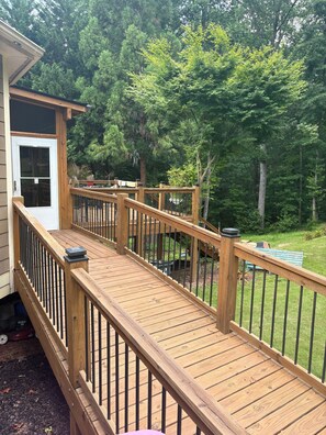 A wooden deck with railings, a door, and a view of a lush green yard with trees. - Splendidly peaceful, spacious house just far away from hustle-bustle! (Braselton)