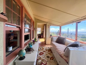Una habitación acogedora con sofá, ventana con vistas, una mesita con un globo terráqueo y una planta en maceta.