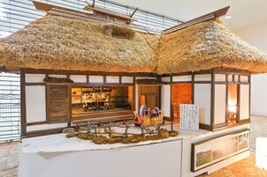 Una estructura tradicional japonesa con tejado de paja, paredes de madera y una exhibición de artefactos culturales.