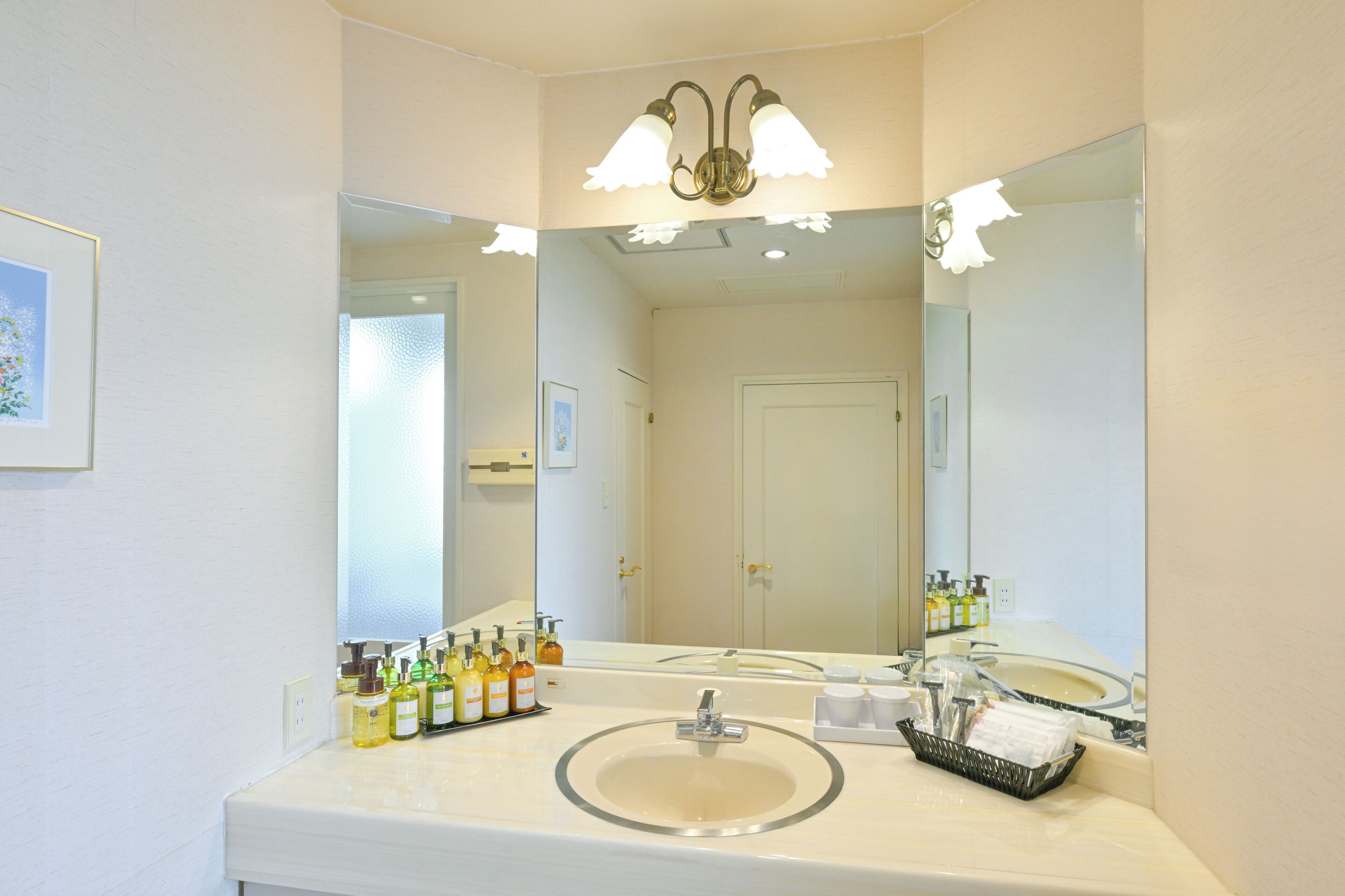 A bathroom with a large mirror, a sink, and toiletries on the counter.