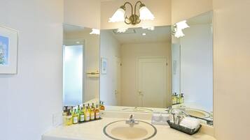 A bathroom with a large mirror, a sink, and toiletries on the counter.