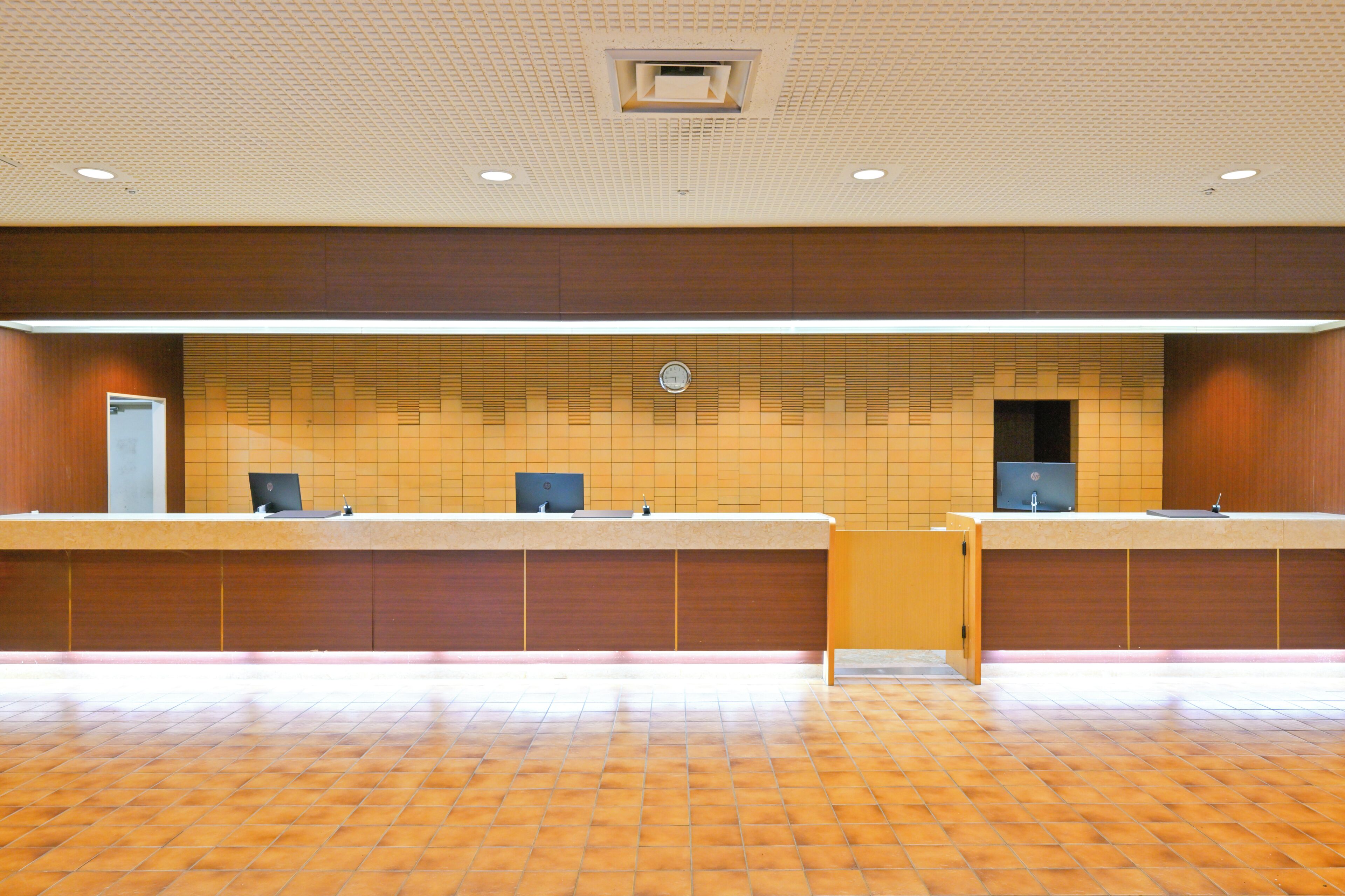 A reception area with a tiled wall, a reception desk, and a clock.