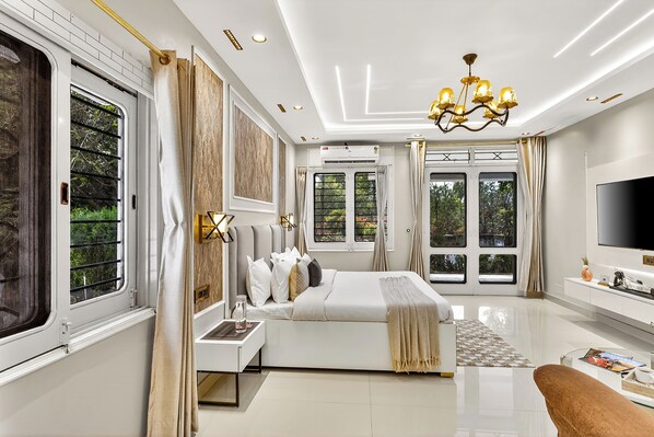 Un dormitorio moderno con una cama grande, mesitas de noche, un televisor y vistas al exterior.