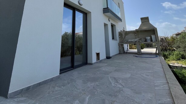A modern two-story building with a flat roof, large windows, and a covered outdoor area.