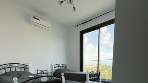 A modern bedroom with a bed, bedside table, and a large window. - Villa - Modern 4 Bedroom (Kissonerga)
