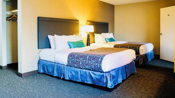Quarto de hotel com duas camas, um guarda-roupa e uma lâmpada.