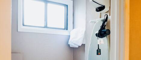 A small bathroom with a toilet, a window, and a towel hanging on the wall.