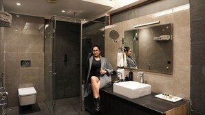A modern bathroom with a glass shower enclosure, a sink with a mirror, and a towel rack. - DLS Forest Vines Resort & Spa (Ramnagar)
