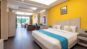 A hotel room with a large bed, a desk, a chair, and a view of the outdoors. - DLS Forest Vines Resort & Spa (Ramnagar)