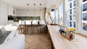 Eine moderne Küche mit weißen Schränken, einer Holzausziehtafel und einem Essbereich mit weißen Stühlen.