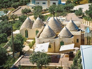 Ein traditionelles Steinhaus mit Kegeldächern, einem gepflasterten Innenhof und einem Pool.