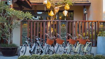 A row of bicycles with baskets, a decorative fence, and hanging lanterns.