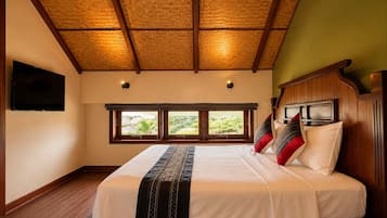 A bedroom with a large bed, wooden headboard, two windows, and a television on the wall.