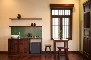 Cocina compacta con un lavamanos, un refrigerador pequeño, una ventana con rejas y una mesa de madera.