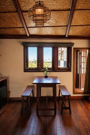 A room with a wooden table, two benches, a window with a view, and a woven ceiling. - Sola Hoi An (Da Nang Municipality)
