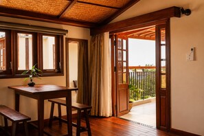 A room with a wooden table, a potted plant, and a view of a balcony with a fence. - Sola Hoi An (Da Nang Municipality)