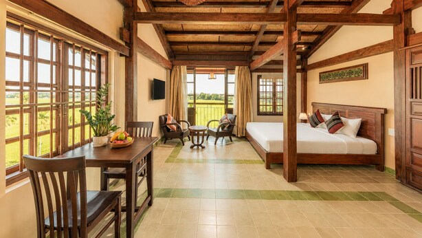 Una habitación con cama, una mesa de comedor con sillas, una mesita con frutero y vistas al exterior.