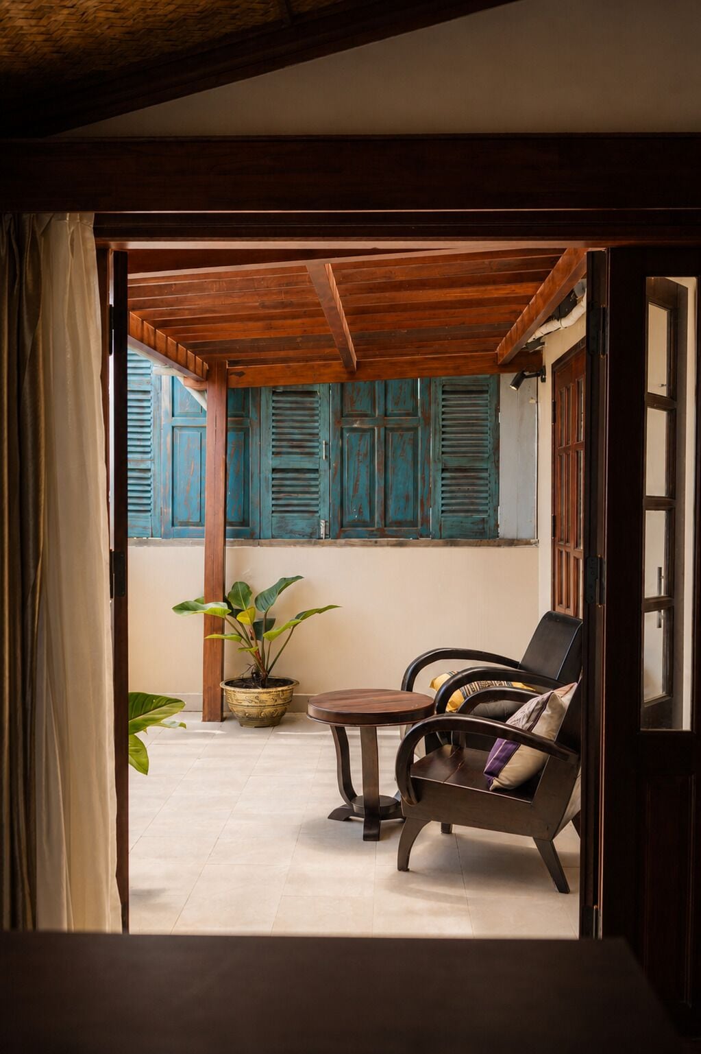 Un umbral abierto que da a una habitación con techo de madera, una mesa, una silla y una planta en maceta.