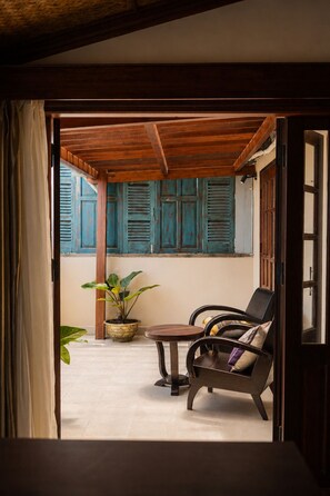 An open doorway leading to a room with a wooden ceiling, a table, a chair, and a potted plant. - Sola Hoi An (Da Nang Municipality)
