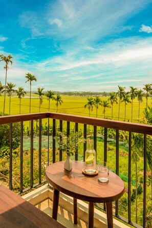 Een balkon met een tafel, een glas water en een bloemenvaas.