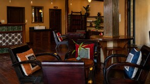 Un hall de hotel con mostrador de recepción, zona de estar y un bar.