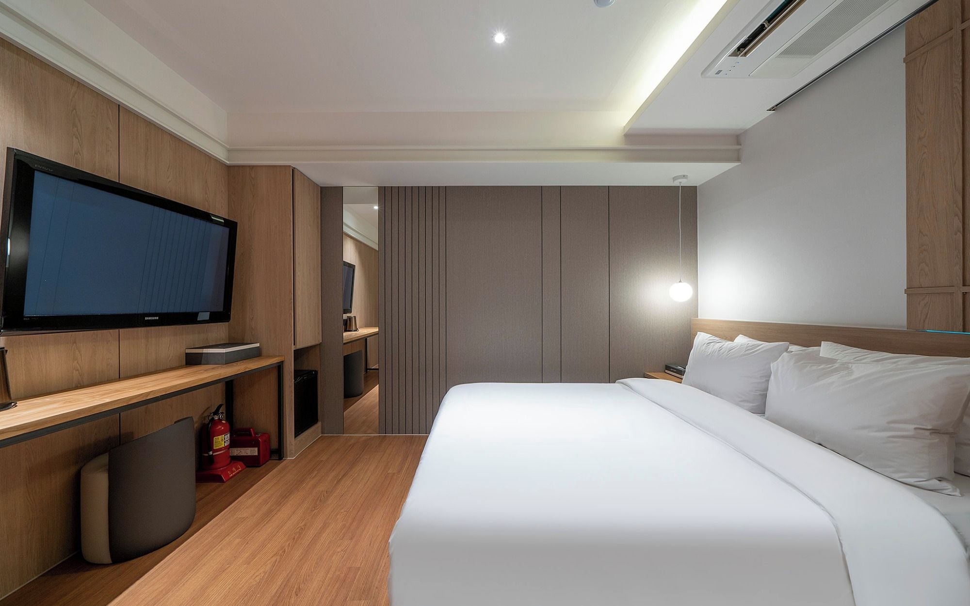 Una habitación de hotel moderna con una cama grande, un televisor, un escritorio y un guardarropa.