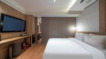 Una habitación de hotel moderna con una cama grande, un televisor, un escritorio y un guardarropa.