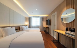 A hotel room with two beds, a TV, a desk, a mirror, and a window with curtains. - Busan Yongho-dong Athena Hotel (Busan)