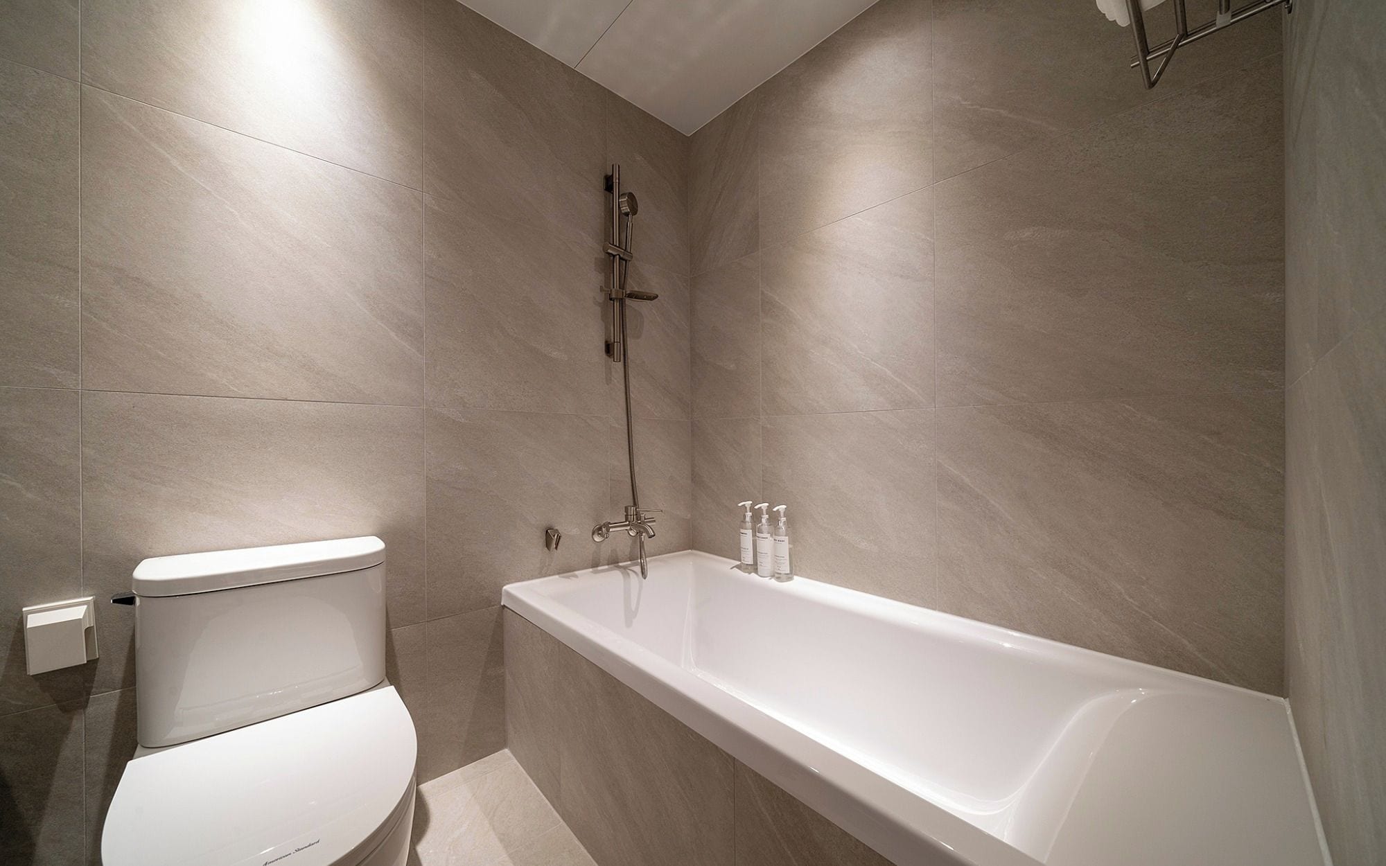 A modern bathroom with a white toilet, a bathtub, and a shower.