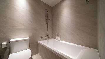 A modern bathroom with a white toilet, a bathtub, and a shower.