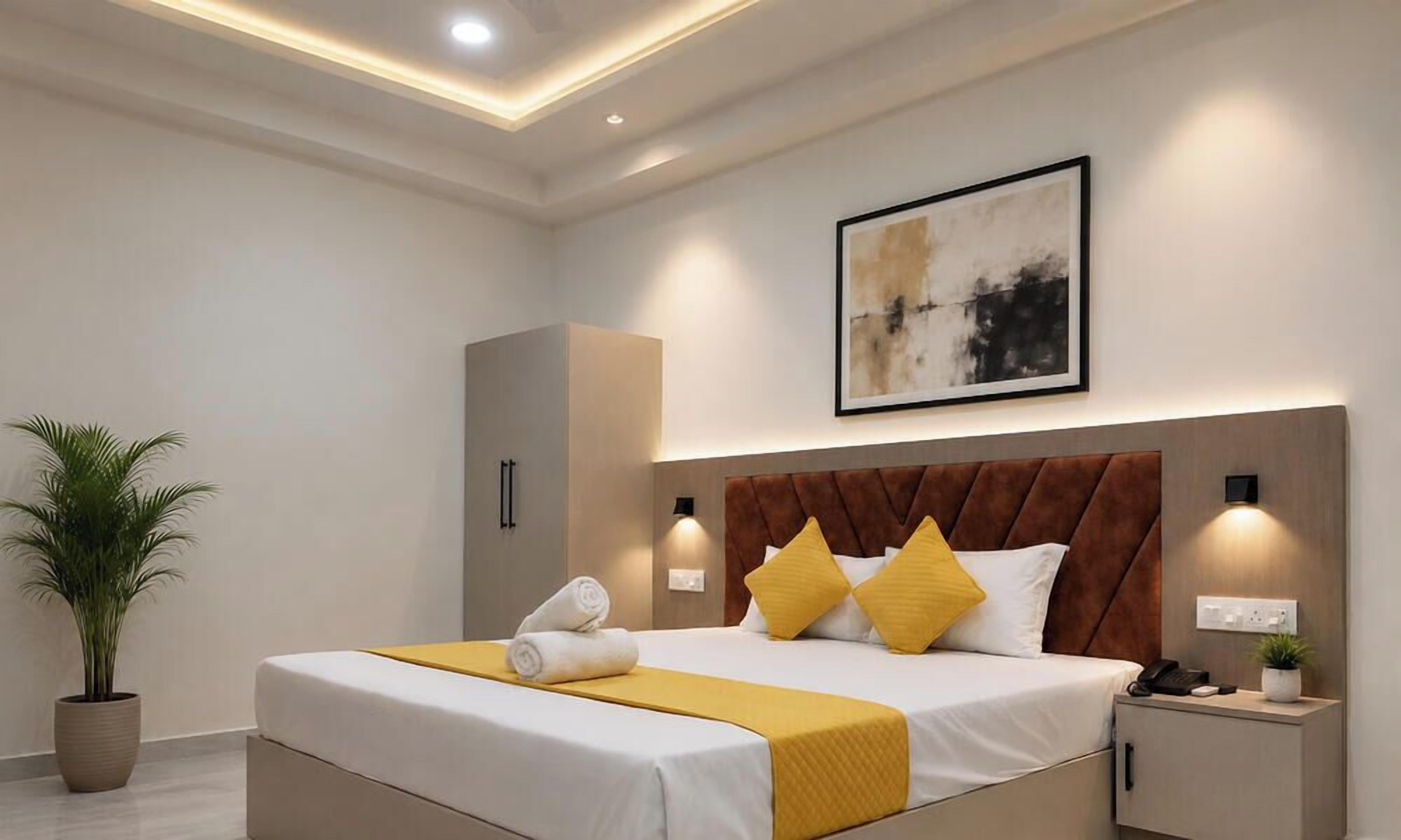 Une chambre d’hôtel moderne avec un grand lit, des lampes de chevet, une plante en pot et un tableau abstrait encadré accroché au mur.