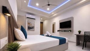 Une chambre d’hôtel moderne équipée d’un lit, d’un bureau, d’une chaise, d’un téléviseur à écran plat et d’un ventilateur de plafond.