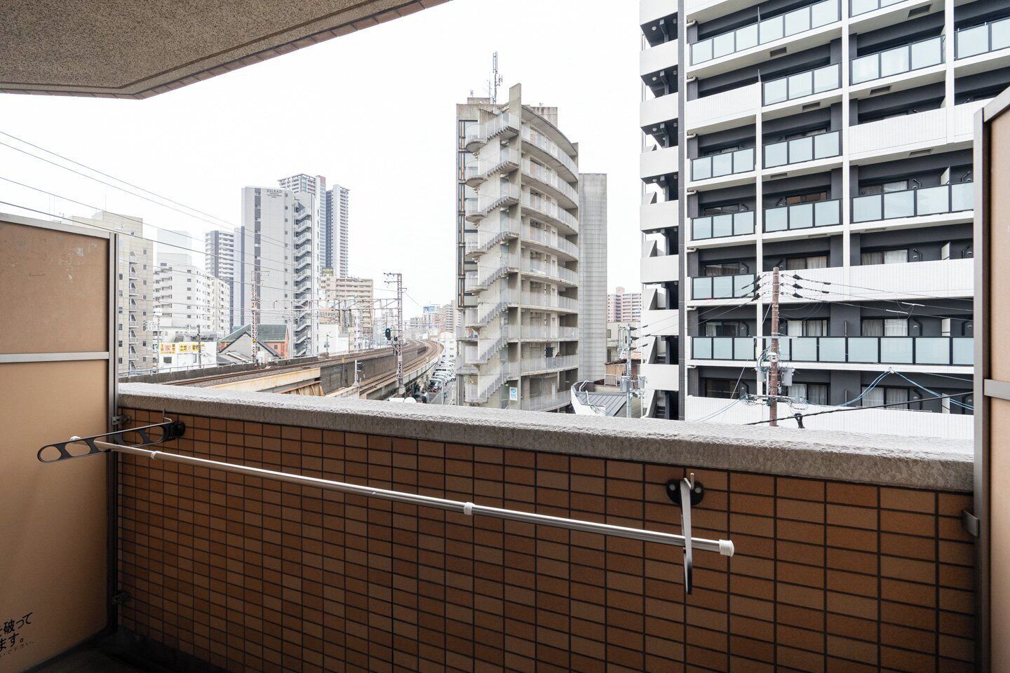 A high-rise building with multiple balconies, a tiled wall, and a metal railing.