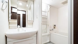 A bathroom with a white sink, mirror, and shower. - AXIA (Osaka)
