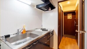 A compact kitchen with a stainless steel sink, a stove, and a black range hood. - AXIA (Osaka)