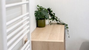 A white radiator, a wooden cabinet, a potted plant, and a woven mirror on the wall. - T3 modern terrace + parking - Marseille 9e (Marseille)
