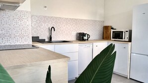 A modern kitchen with a wooden countertop, white cabinets, a dishwasher, a coffee maker, and a microwave. - T3 modern terrace + parking - Marseille 9e (Marseille)
