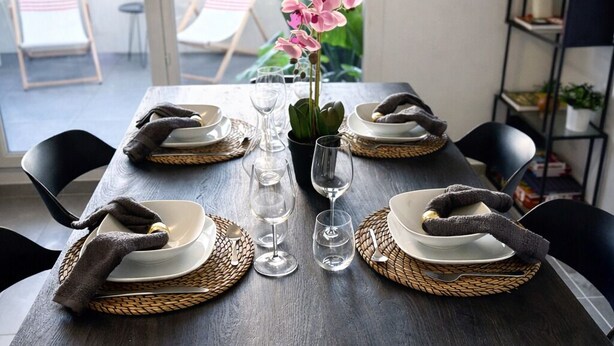A dining table set with plates, glasses, and a vase of flowers. - T3 modern terrace + parking - Marseille 9e (Marseille)