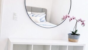 A white console bed with a grey headboard, a round mirror on the wall, and a potted plant on the console. - T3 modern terrace + parking - Marseille 9e (Marseille)