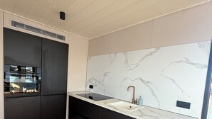 A modern kitchen with a marble backsplash, black cabinetry, and a built-in oven. - Unique stay on the water, houseboat Loosdrecht (Loosdrecht)
