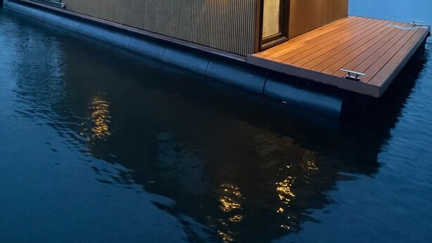 A modern floating house with a wooden deck, large windows, and warm lighting. - Unique stay on the water, houseboat Loosdrecht (Loosdrecht)