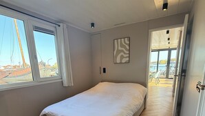 A bedroom with a bed, a window, a door, and a view of the outside. - Unique stay on the water, houseboat Loosdrecht (Loosdrecht)