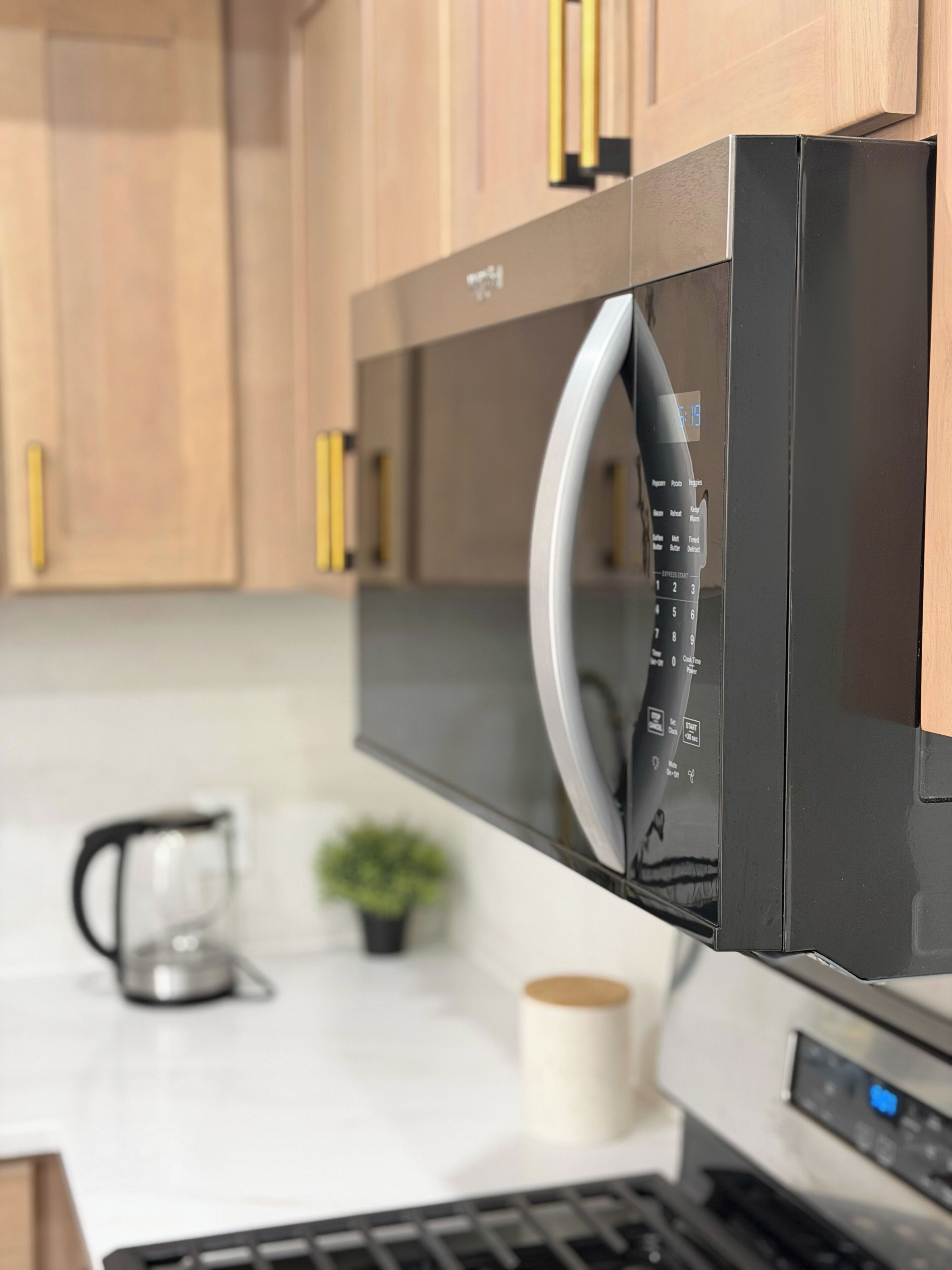 Une cuisine moderne équipée d’un four à micro-ondes encastré, d’une machine à café et d’une petite plante en pot.