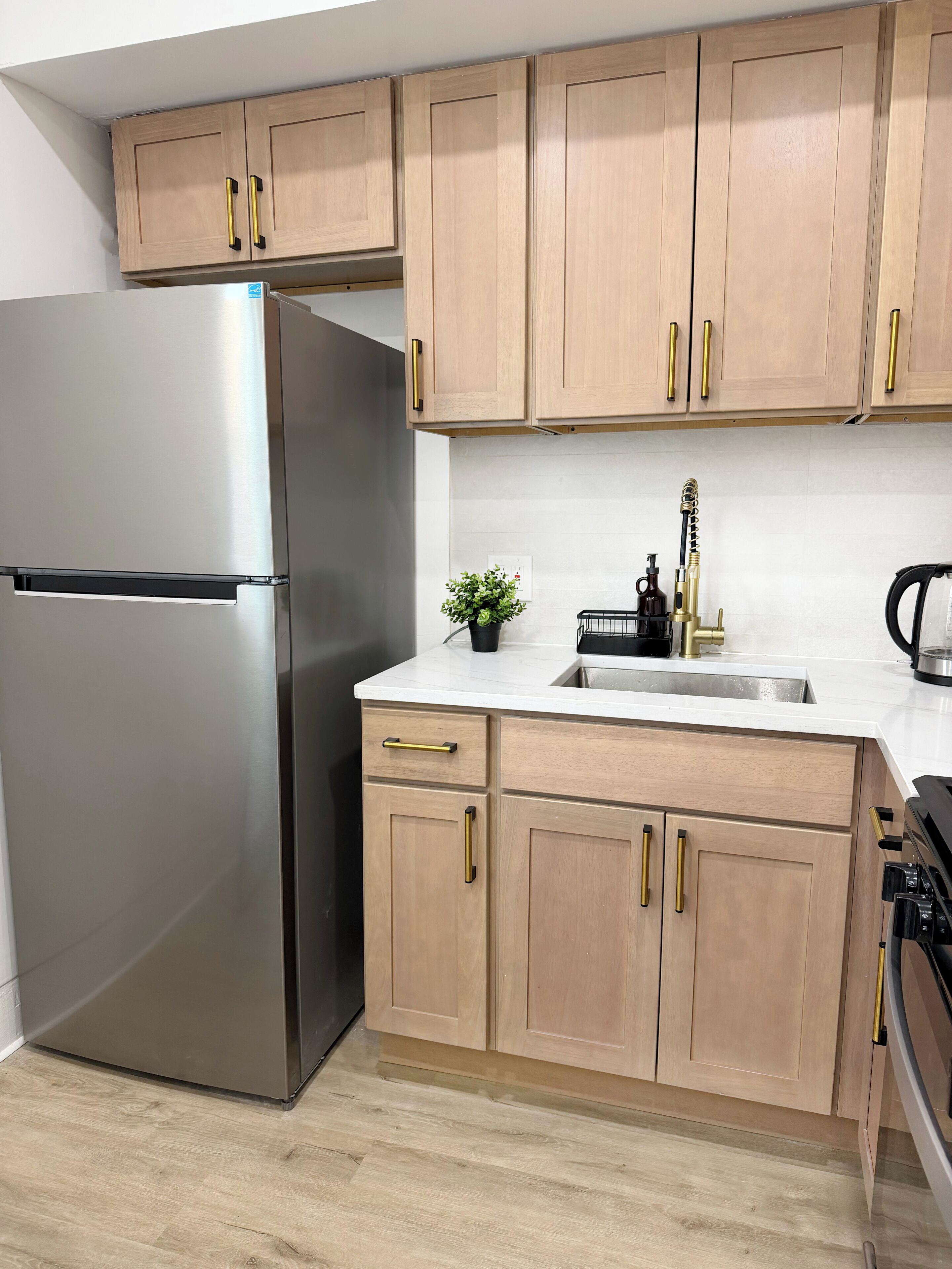 Una cocina con armarios de madera, un refrigerador de acero inoxidable, un fregadero y una estufa.