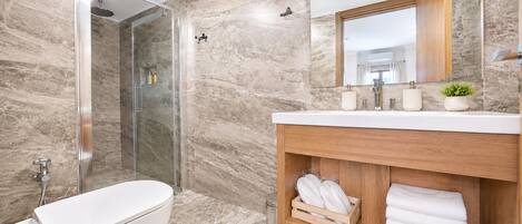 A modern bathroom with a glass-enclosed shower, a white bathtub, and a wooden vanity with a mirror.