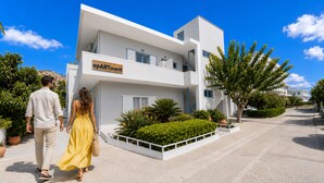 Um edifício moderno de dois andares com uma placa que diz 'APARTMENT' e uma área de jardim ajardinada.