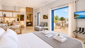 Quarto de hotel com cama, área de refeições, cozinha e varanda com vista.