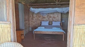 A wooden room with a bed, a small table, and a chair. - Anake Lodge (Cape Maclear)